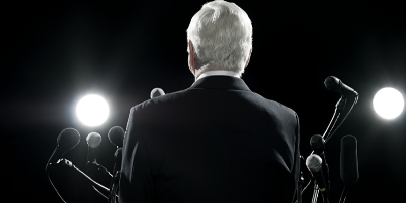 a man in a suit and tie holding a microphone 